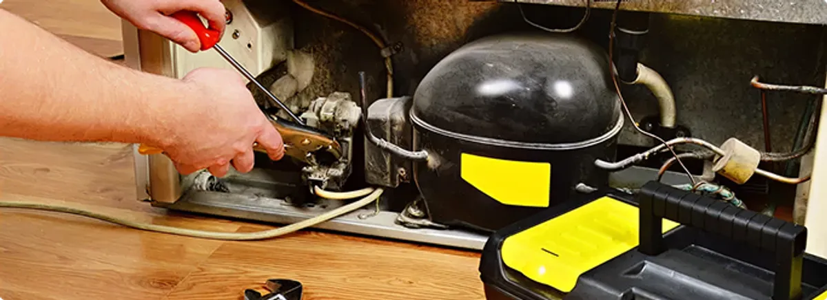 Refrigerator repair technician fixing the compressor and wiring in Albany, NY